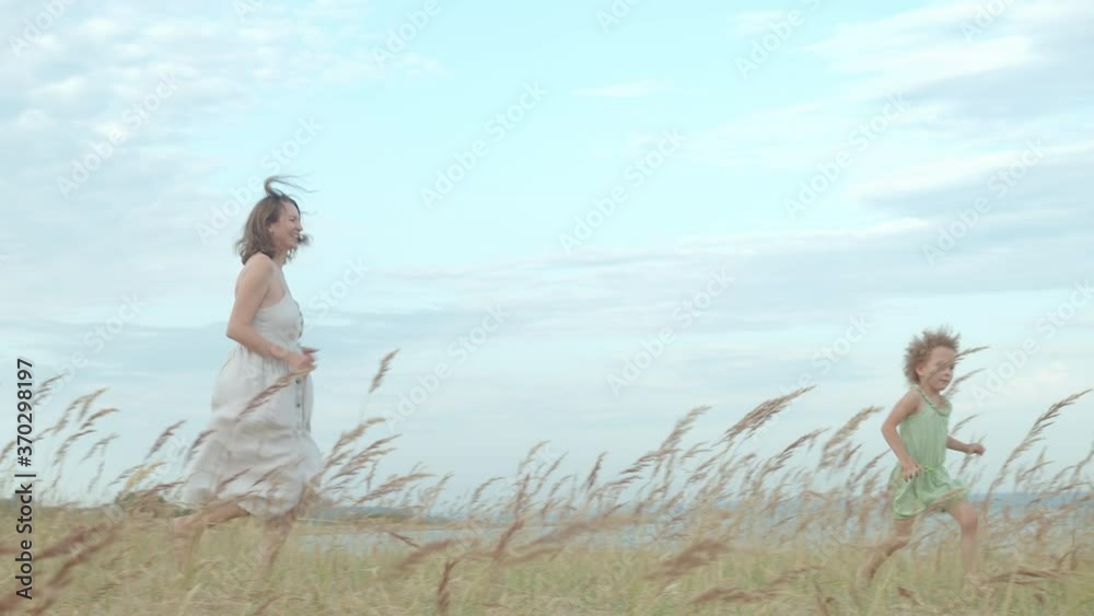 Mother daughter beach. Pretty mom running with curly girls in nature. Dry grass meadow. Mother daughter beach. Pretty mom running with curly girls in nature. Dry grass meadow.