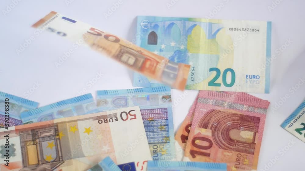 Close-up shot of euro banknotes falling on white table Close-up shot of euro banknotes falling on white table