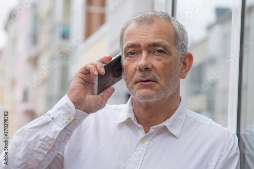 senior man using mobile phone in the city