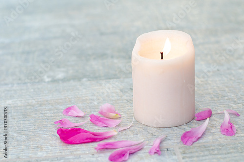 Beautiful pink peony petals and white candle on white grey stone background with copy space for your text top view. Greeting card, SPA and romantic concept.