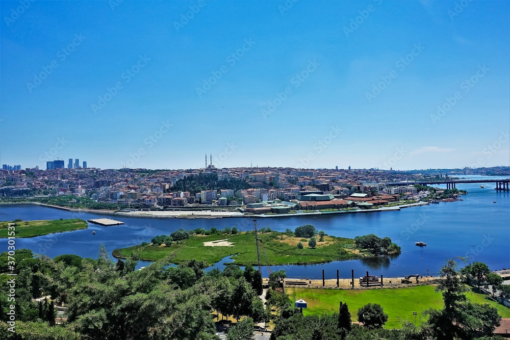 Panorama of Istanbul, summer sunny day. Bright blue Golden Horn Bay, green islands. In the distance there are many residential buildings, skyscrapers, mosques. Clear blue sky. Turkey.