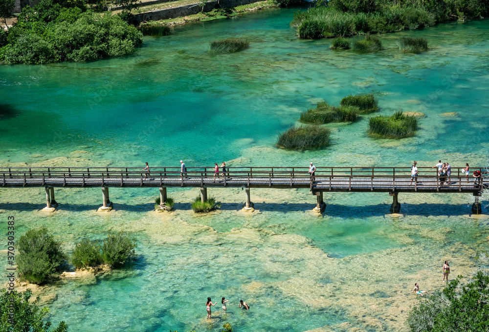 CROATIA, SKRADINSKI BUK - 6/23/2020: Wooden bridge and people bathing in Krka National Park in Croatia. Sunny day, overhead view. 