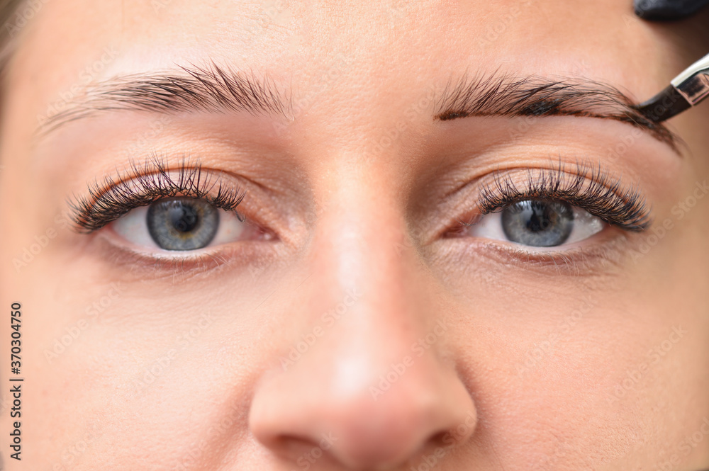 Eyes and eyebrows of a young woman while coloring eyebrows in a beauty salon Eyes and eyebrows of a young woman while coloring eyebrows in a beauty salon