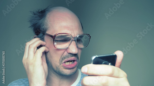 balding man with glasses hardly uses a smartphone. Humor photo