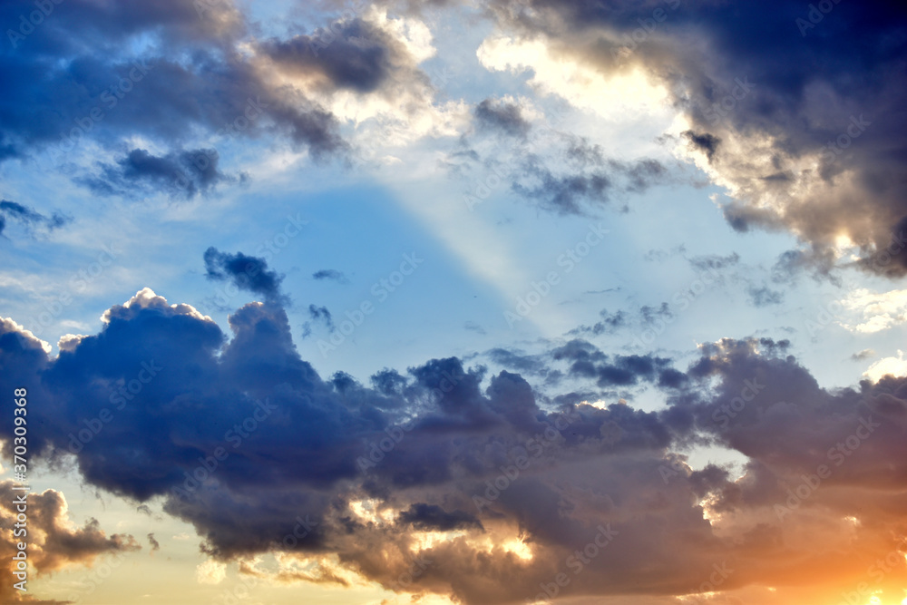 Obraz premium Evening sunset sky with yellow blue clouds and sun rays
