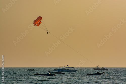 parasailing over the blue sea at sunset
