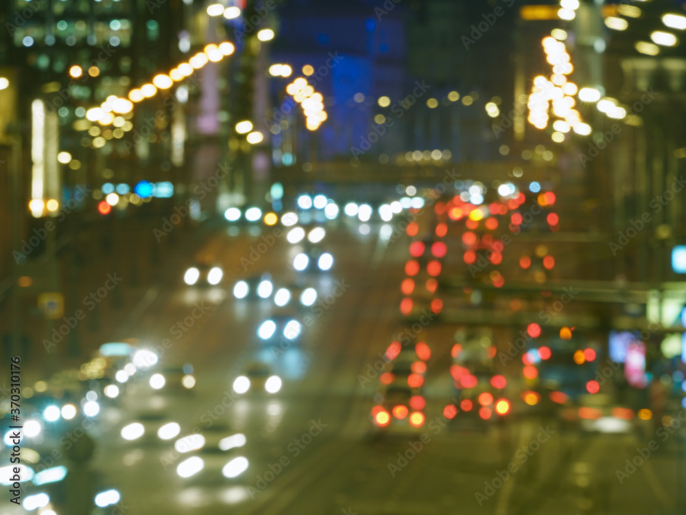 Defocused photography of Moscow cityscape in night time. Big traffic. Street is filled with cars. Blurred motion of cars at motorway. Illuminated buildings. Back / rear view