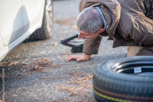 Man changing flat tire on the road