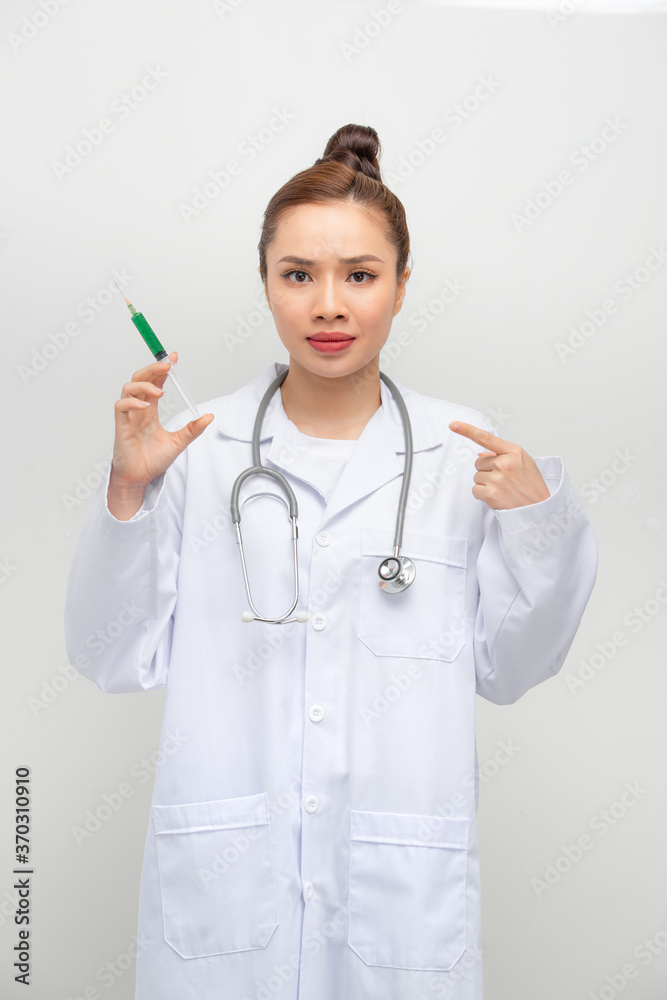 Doctor woman holding syringe with hand pointing, shocked with shame and surprise face, angry and frustrated. Fear and upset for mistake. Doctor woman holding syringe with hand pointing, shocked with shame and surprise face, angry and frustrated. Fear and upset for mistake.