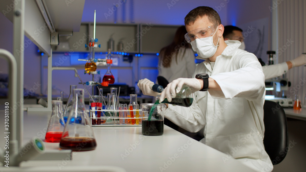 Young scientist mixing colored liquids in a flask. Young scientist mixing colored liquids in a flask.