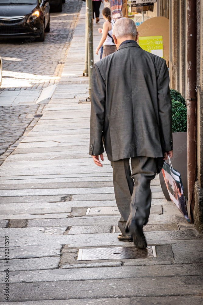 Grey Haired Man In Suit Walking Down European Sidewalk, Portugal