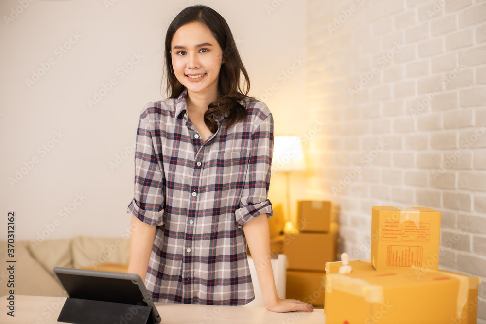 Worker In Warehouse Checking Boxes Using Digital Tablet.Start up small business entrepreneur SME or freelance woman working at home concept, Young Asian small business owner,online marketing. Worker In Warehouse Checking Boxes Using Digital Tablet.Start up small business entrepreneur SME or freelance woman working at home concept, Young Asian small business owner,online marketing.
