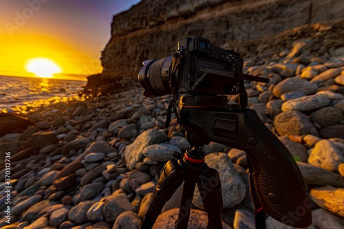 camera recording video of the sunset on the beach of mogan with beautiful lights and colors due to the fall of the sun that is about to hide on the horizon photo