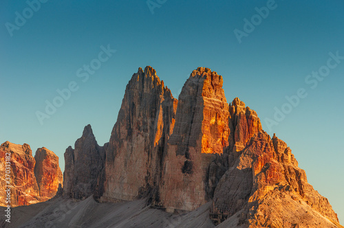 Beautiful sunset in magical Three Dolomite peaks at the national park Three Peaks (Tre Cime, Drei Zinnen) in Autumn colors at blue sky, South Tyrol, Italy, details