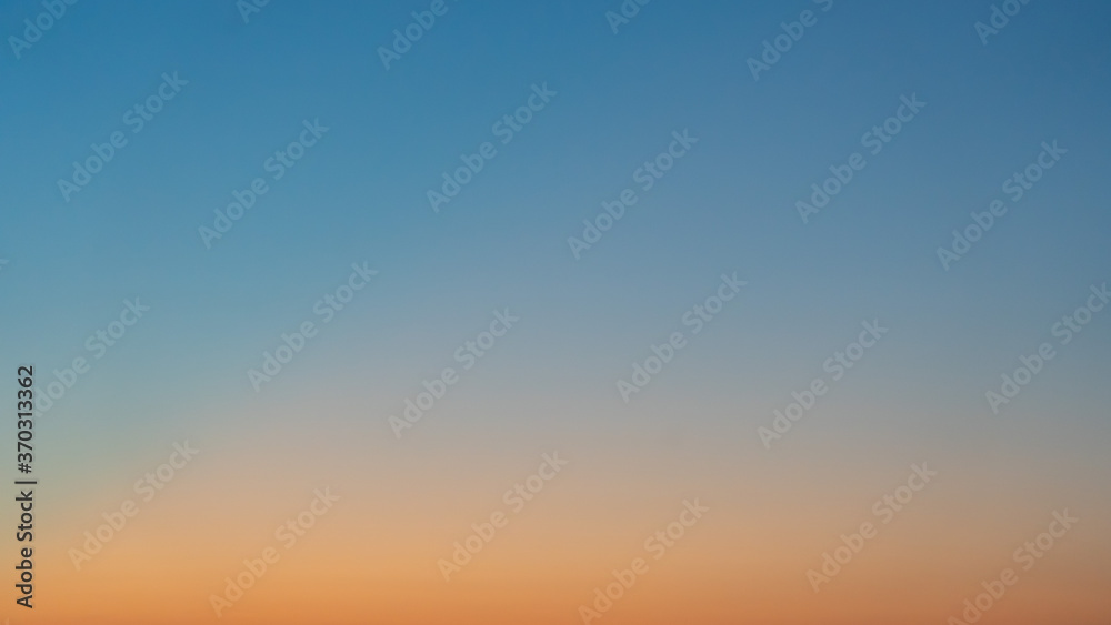 Natural background. The sky before sunrise. The firmament after sunset. Colored smooth transitions from blue to orange. Colorful clear sky with no clouds at dusk after sunset.