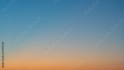 Natural background. The sky before sunrise. The firmament after sunset. Colored smooth transitions from blue to orange. Colorful clear sky with no clouds at dusk after sunset. © woff