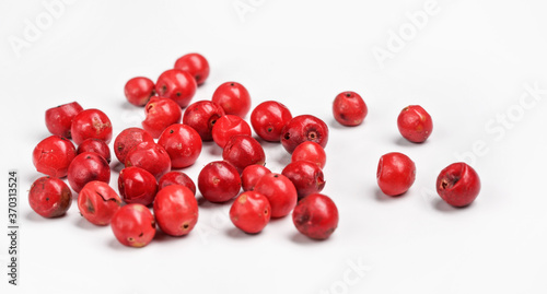 Red or Pink peppercorn scattered on board, closeup photo isolated with white background