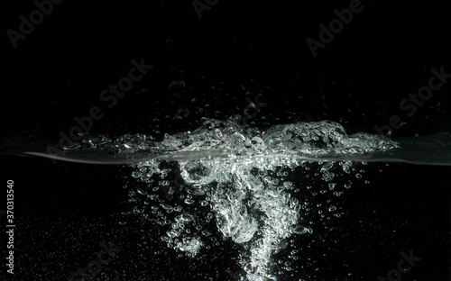 Water splashing as it's poured into aquarium tank, black background © Lubo Ivanko