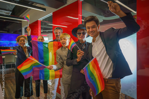 diverse group of lgbtq people with rainbow flag on hand team up together