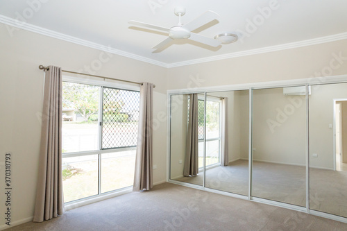 Bedroom in new house with ceiling fan, sliding glass mirrors doors and sliding glass windows