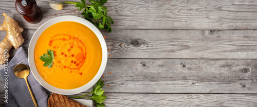 Top view of winter spicy lentil soup on graw wooden background