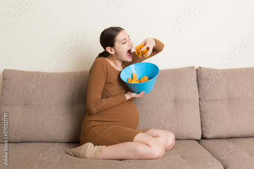 Canvas Print Pregnant woman is eating potato chips because of salt cravings