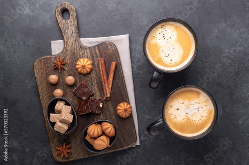 Two cups with coffee, brown sugar and various sweets on stone background. Top view. Copy space