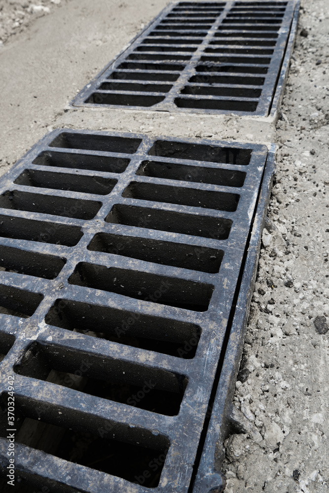New rainwater grate on the road or sidewalk, installation in concrete. City sewage system for draining water during heavy rain New rainwater grate on the road or sidewalk, installation in concrete. City sewage system for draining water during heavy rain