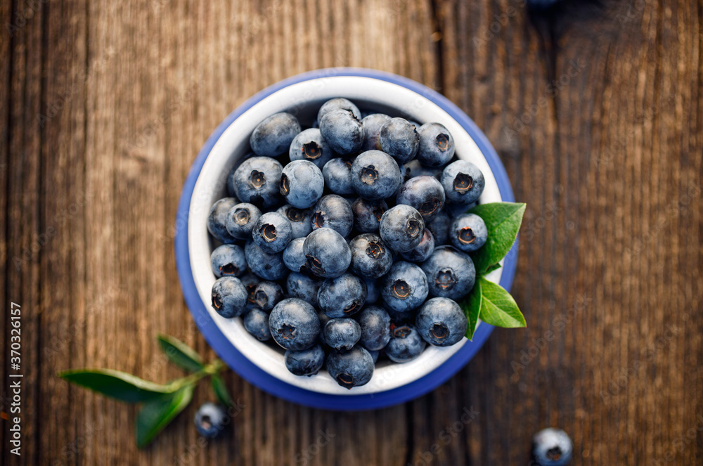 Fresh blueberries in a ceramic bowl on a wooden table top view Fresh blueberries in a ceramic bowl on a wooden table top view