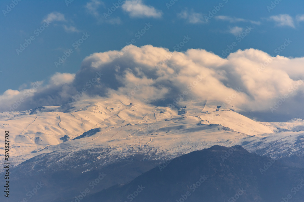 View of Sierra Nevada with snow and clouds hiding the peaks.