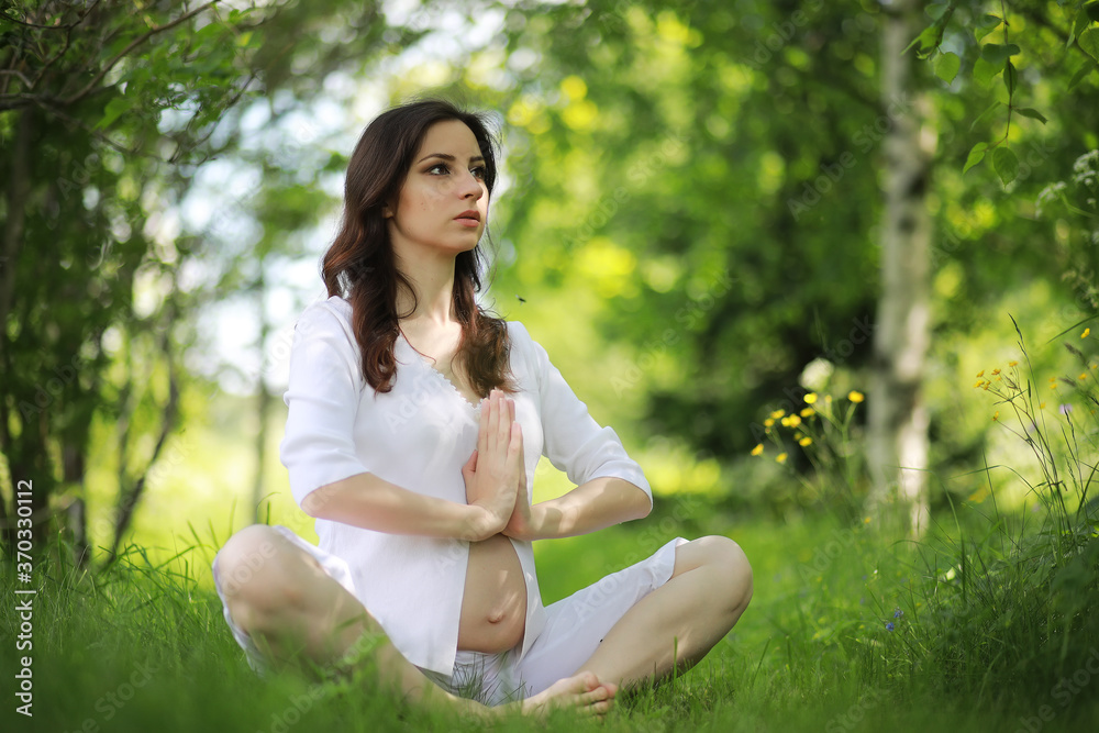 Pregnant woman doing yoga exercise in nature on a summer Pregnant woman doing yoga exercise in nature on a summer