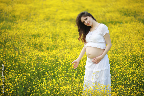 Pregnant woman in a dress in a field of flowers © alexkich