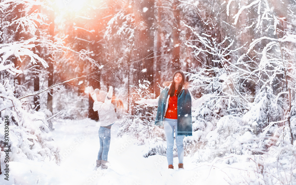 Young family for a walk. Mom and daughter are walking in a winter park. Young family for a walk. Mom and daughter are walking in a winter park.
