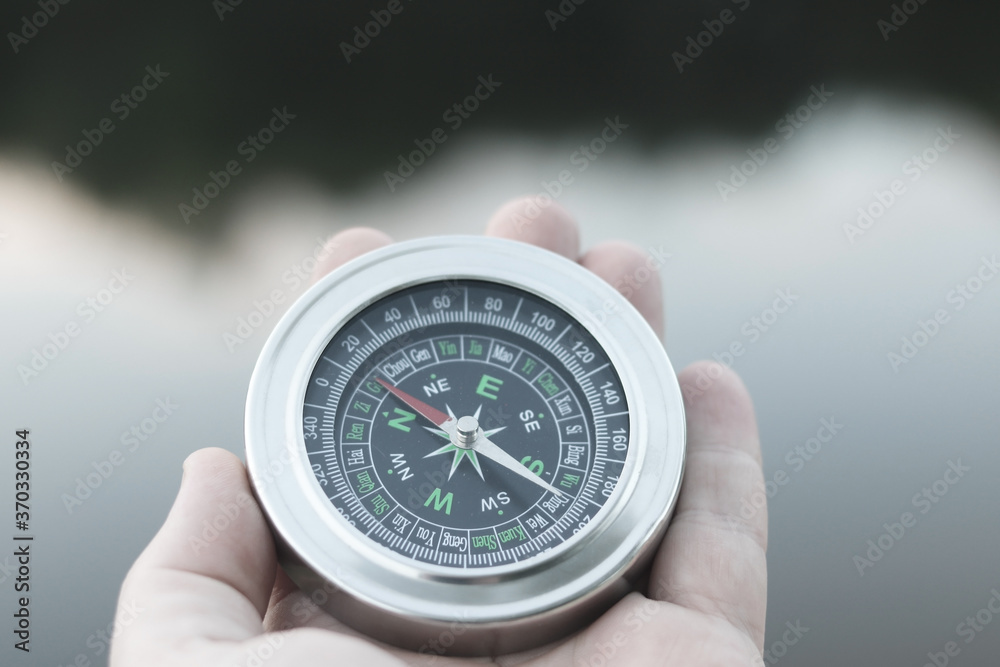 Old classic navigation compass in hand on natural background as symbol of tourism with compass, travel with compass and outdoor activities with compass Old classic navigation compass in hand on natural background as symbol of tourism with compass, travel with compass and outdoor activities with compass