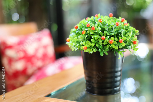 Copy space of fake flower bush in flowerpot on table with bokeh. Concept for interior design,cafe and restaurant decoration, space for text.