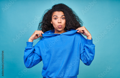A funny teenage girl in a casual blue sweatshirt making grimaces.