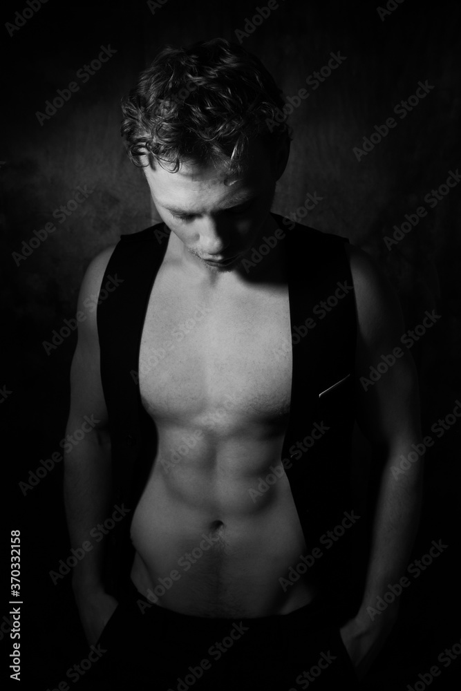 Fototapeta premium Handsome male with open waistcoat revealing defined pecs and muscular sixpack abs looking down