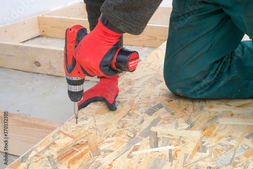 Fotografija Man worker screws wooden oriented stands bords on insulated floor