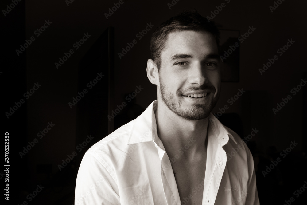 Fototapeta premium Portrait of handsome smiling young man with open shirt looking at camera