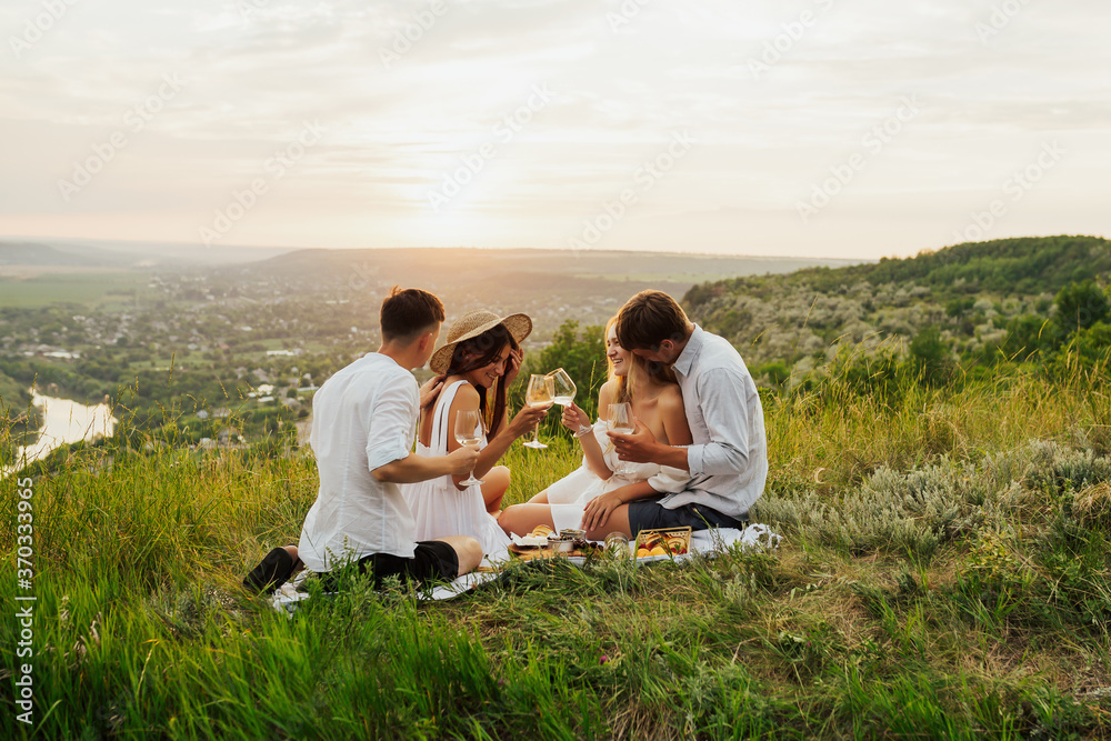 Cheerful friends enjoying a leisurely picnic on the mountain with beautiful landscape. They having a picnic and having fun. Copy space.
