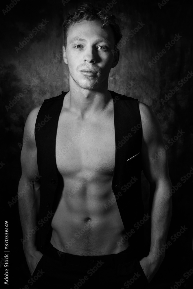 Handsome male with open waistcoat revealing defined pecs and muscular sixpack abs looking at camera Handsome male with open waistcoat revealing defined pecs and muscular sixpack abs looking at camera