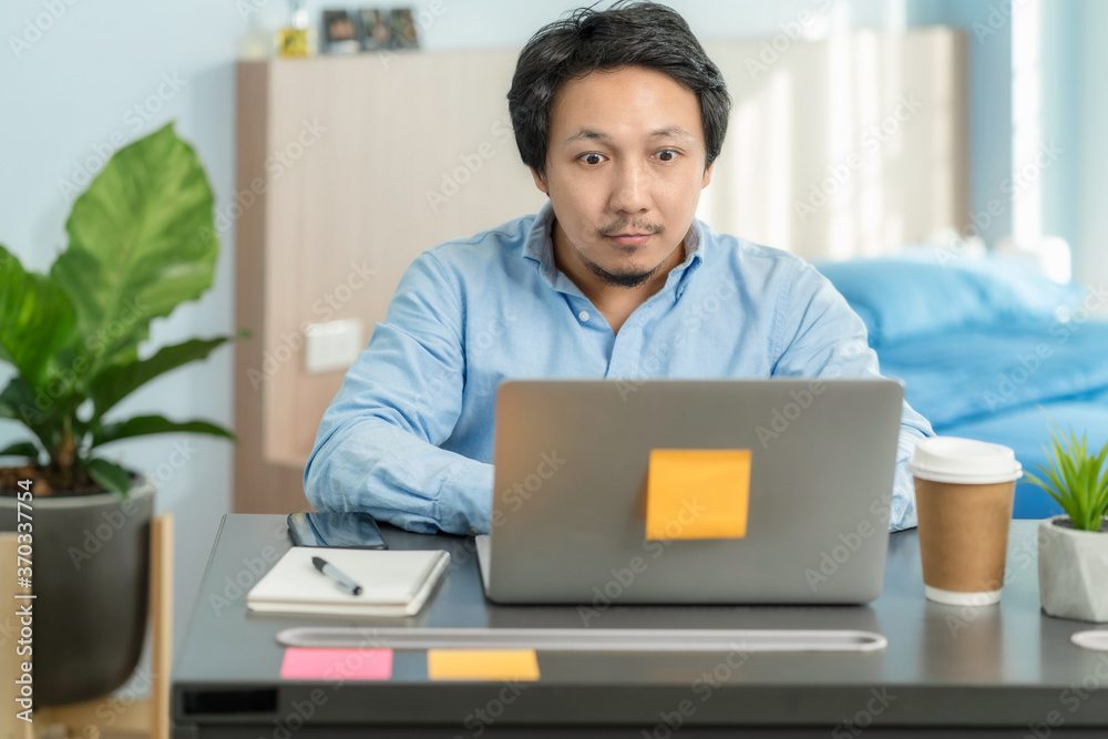 Asian business man using technology laptop and working from home with surprise action in bedroom of house by video conference call,startups and business owner,social distance and new normal concept Asian business man using technology laptop and working from home with surprise action in bedroom of house by video conference call,startups and business owner,social distance and new normal concept