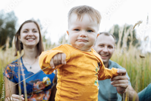 happy family having fun outdoors in grass. Family enjoying life together at meadow. Mother  father  little boy smiling while spending free time outdoors