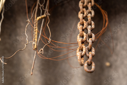 Hanging old thick metal iron rusty chains with another thin rusty metal wires of different shapes, scrap metal, view from below, horizontal industrial background