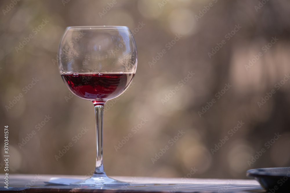 A glass of red wine with a natural bokeh background