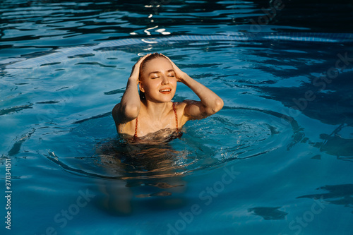 Young blonde woman swimming in a pool, outdoors.