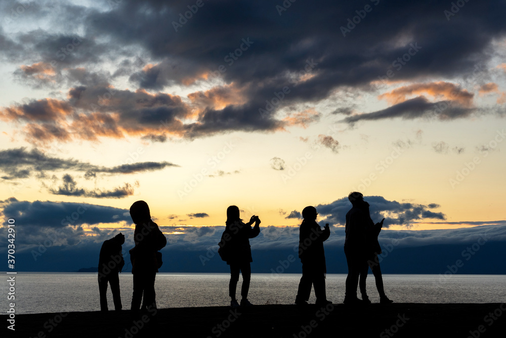 Faceless group of people on top of a mountain watching sunset, silhouette of group of people taking pictures outside during sunrise or sunset
