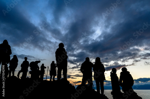 Faceless group of people on top of a mountain watching sunset, silhouette of group of people taking pictures outside during sunrise or sunset