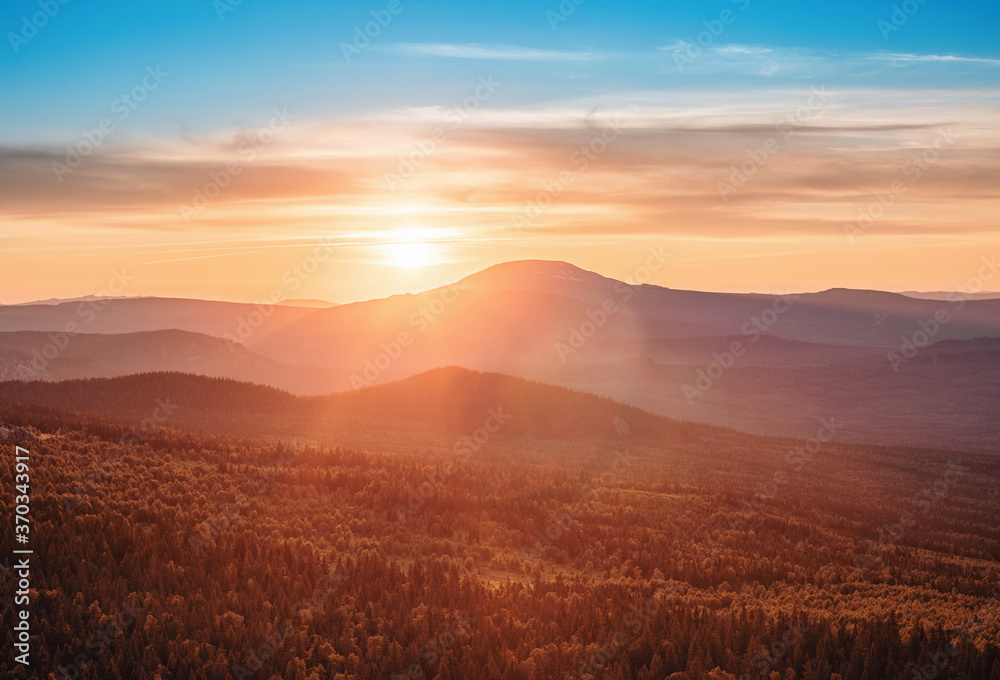 A rocky mountain range covered in the wild woods illuminated by the golden light of the setting sun. A natural Park reserve or hunting grounds. Recreational outdoor tourism A rocky mountain range covered in the wild woods illuminated by the golden light of the setting sun. A natural Park reserve or hunting grounds. Recreational outdoor tourism