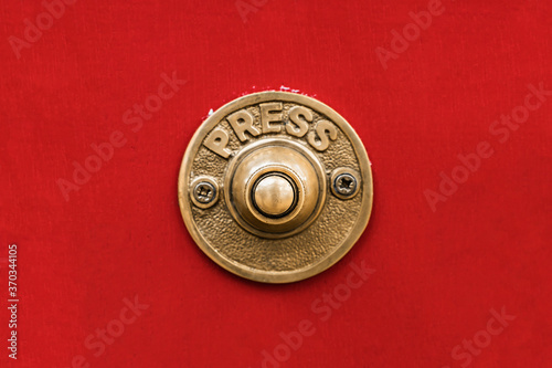 Fototapeta Classic traditional rustic heavy cast brass doorbell button on a seamless red wall shot straight on